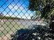 Community tennis court with a green surface, surrounded by fencing and mature trees at 3142 Espanol Dr, Las Vegas, NV 89121