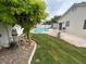 Landscaped backyard with a kidney-shaped pool, mature tree, and equipment near the home's exterior at 3729 Bronco Billy Ct, Las Vegas, NV 89129