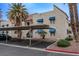 Apartment building exterior with covered parking, lush landscaping, and blue awnings at 5040 Spencer St # D, Las Vegas, NV 89119