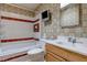 A bathroom with a tub and shower combination, toilet, and sink with a wooden cabinet at 5262 Harris Ave, Las Vegas, NV 89110
