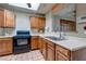 Well-lit kitchen with wood cabinets, black appliances, tile floors, and a double sink at 5262 Harris Ave, Las Vegas, NV 89110