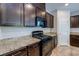 Modern kitchen with granite countertops, gas range, black appliances, and dark wood cabinets at 5412 Dalle Valley St, North Las Vegas, NV 89031