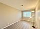 A bright bedroom with light gray wood flooring and a large window overlooking the greenery outside at 6420 Little Pine Way, Las Vegas, NV 89108