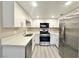 Well-lit kitchen with stainless steel appliances, white cabinetry, modern countertops and gray laminate flooring at 6420 Little Pine Way, Las Vegas, NV 89108
