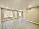 Open living room with gray wood-look flooring, neutral paint, and bright natural light from front windows at 6420 Little Pine Way, Las Vegas, NV 89108
