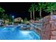 Inviting community pool at night with a rock waterfall feature and lounge chairs at 8250 N Grand Canyon Dr # 2154, Las Vegas, NV 89166