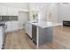 Open kitchen with white cabinets, stainless steel appliances, an island with a breakfast bar, and hardwood floors at 8847 W Katie Ave, Las Vegas, NV 89147