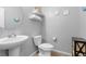 A small powder room with decorative light fixtures, floating shelves, and a pedestal sink at 8953 Hitch Creek St, Las Vegas, NV 89131