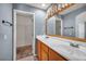 Bathroom featuring a double vanity, oak cabinets, and a large mirror at 9165 Starling Wing Pl, Las Vegas, NV 89143