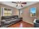 Comfortable living room features hardwood floors, a ceiling fan, and abundant natural light from three windows at 9165 Starling Wing Pl, Las Vegas, NV 89143