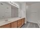 Bathroom featuring double sinks with wood cabinets, large mirror, and grey wood-look flooring at 9330 W Maule Ave # 212, Las Vegas, NV 89148