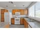 Bright kitchen featuring wooden cabinets, white appliances, gray countertops, and a window over the sink at 9330 W Maule Ave # 212, Las Vegas, NV 89148