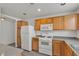 Bright kitchen featuring wooden cabinets, white appliances, gray countertops, and a view into the dining area at 9330 W Maule Ave # 212, Las Vegas, NV 89148