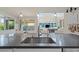 Close up view of a gray kitchen island with sleek faucet hardware and dining area with backyard view at 9654 Ponderosa Skye Ct, Las Vegas, NV 89166