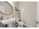 Clean powder room with pedestal sink, toilet, round mirror, and stylish decorative accents at 9654 Ponderosa Skye Ct, Las Vegas, NV 89166