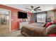 Main bedroom with dark red walls, ceiling fan, large bed, and TV at 9931 Cherry Melee Ave, Las Vegas, NV 89148