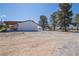 Backyard of home with white siding, dark roof, carport, desert landscape, and parked vehicles at 1050 Bruce St, Pahrump, NV 89048