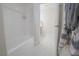 Bathroom with a white tub and shower, white tile and a glimpse into a vanity area with a gray and white towel at 1050 Bruce St, Pahrump, NV 89048