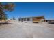 Wide view of a single story home with white siding, dark roof, shutters, ample parking and a desert landscape at 1050 Bruce St, Pahrump, NV 89048