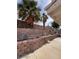 Backyard featuring mature trees and brick retaining wall at 128 Appian Way, Henderson, NV 89002