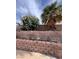 Backyard featuring mature trees and brick retaining wall at 128 Appian Way, Henderson, NV 89002