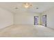 Large bedroom with neutral carpeting, natural light from the sliding door and a ceiling fan at 1931 Pago Ct, Las Vegas, NV 89117