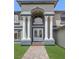 Close-up of home's entry featuring an impressive portico, decorative double doors, and manicured lawn at 358 Whispering Tree Ave, Las Vegas, NV 89183