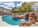 Inviting pool area with a rock waterfall feature, a gazebo, and built-in outdoor grill at 358 Whispering Tree Ave, Las Vegas, NV 89183