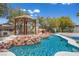 Backyard showcasing a pool, rock features, and covered outdoor space for relaxation at 358 Whispering Tree Ave, Las Vegas, NV 89183