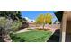 Spacious backyard featuring artificial turf, desert landscaping, block wall, and mature trees at 4619 Reliant St, North Las Vegas, NV 89031
