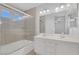 Bright bathroom featuring a double vanity, a large mirror, and a tiled shower-tub combo with glass doors at 4619 Reliant St, North Las Vegas, NV 89031