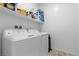 Functional laundry room with white washer and dryer, storage shelves, and tiled floors at 55 Strada Fontana, Henderson, NV 89011