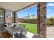 Covered patio with stone pillars, outdoor dining set, built-in grill, and views of the landscaped backyard at 55 Strada Fontana, Henderson, NV 89011