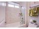 Stylish bathroom features a shower-over-tub with glass door and neutral toned stone-look tile surround at 6060 N Conquistador St, Las Vegas, NV 89149