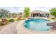 Stunning backyard with a freeform pool, integrated spa, and slide, complemented by lush greenery and a covered patio at 6060 N Conquistador St, Las Vegas, NV 89149