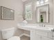 Stylish powder room with a white vanity, modern mirror and sconces, complemented by a decorative vase at 628 Chervil Valley Dr, Las Vegas, NV 89138