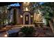 Home entrance at dusk featuring a stone facade, arched doorway, and well-manicured landscaping at 628 Chervil Valley Dr, Las Vegas, NV 89138