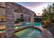Beautiful pool with a stone waterfall feature and inviting spa in a well-manicured backyard at twilight at 628 Chervil Valley Dr, Las Vegas, NV 89138