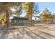 Landscaped front yard featuring a home surrounded by mature trees and chainlink fence at 6920 Bradley Rd, Las Vegas, NV 89131