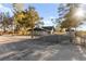 Home with chainlink fence, gravel front yard, mature trees, and outbuilding at 6920 Bradley Rd, Las Vegas, NV 89131