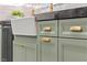 Close-up of sage green kitchen cabinets with granite countertops and gold hardware at 6920 Bradley Rd, Las Vegas, NV 89131