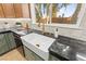 Kitchen sink with white farmhouse basin, gold faucet, granite countertops, and a view of the backyard at 6920 Bradley Rd, Las Vegas, NV 89131