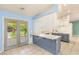Bright kitchen with tiled floors, blue lower cabinets, white upper cabinets, and glass doors to the backyard at 7110 La Cienega St, Las Vegas, NV 89119