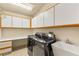 Functional laundry room featuring modern washer/dryer units, upper cabinets, and a utility sink at 7110 La Cienega St, Las Vegas, NV 89119