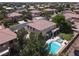 Aerial view of a two-story home with a pool, spa, balcony, lush lawn, and surrounding greenery at 7310 Heggie Ave, Las Vegas, NV 89131