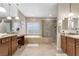 Bathroom with dual sinks, granite countertops, soaking tub, and glass-enclosed shower with tile surround at 7778 Villa Montara St, Las Vegas, NV 89123