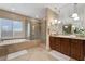Bright bathroom with dual sinks, soaking tub, glass-enclosed shower, and granite countertops at 7778 Villa Montara St, Las Vegas, NV 89123