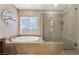 Bright bathroom featuring a jetted tub, glass enclosed shower, and neutral tile work at 7778 Villa Montara St, Las Vegas, NV 89123