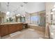 Bright bathroom featuring dual sinks, granite countertops, soaking tub, and glass-enclosed shower at 7778 Villa Montara St, Las Vegas, NV 89123