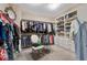 Spacious walk-in closet with custom shelving, ample hanging space, chair and carpeted floors at 7778 Villa Montara St, Las Vegas, NV 89123